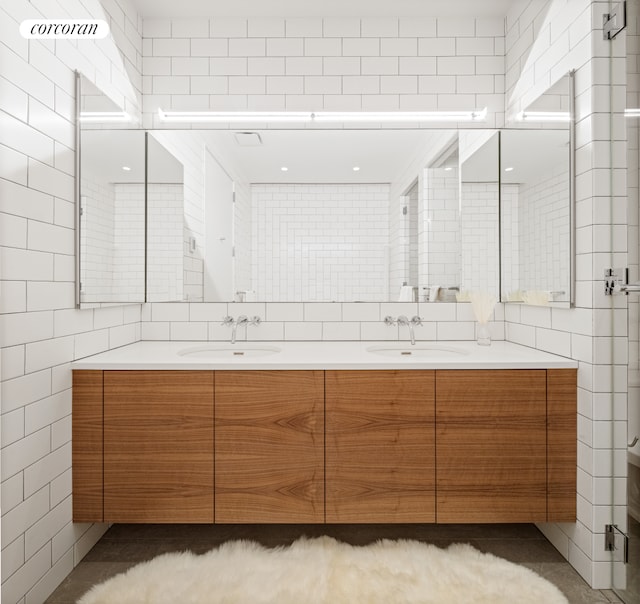 bathroom featuring visible vents, a sink, tile walls, and double vanity