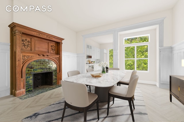 dining space with a decorative wall, a fireplace, and a wainscoted wall