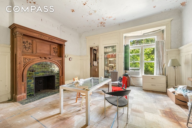 dining area with a decorative wall, cooling unit, a fireplace with flush hearth, and a wainscoted wall