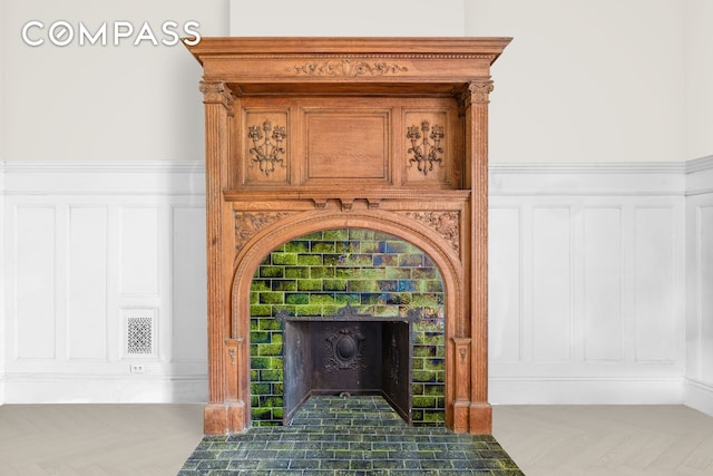 details with a decorative wall, a fireplace with flush hearth, and visible vents