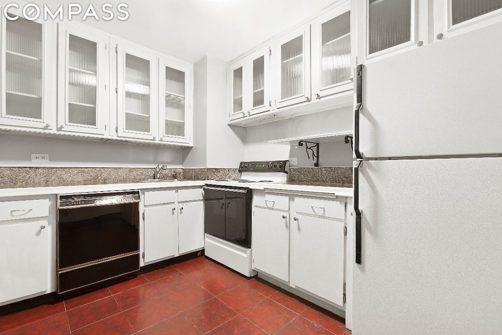 kitchen with white cabinetry, sink, dark tile patterned floors, and white appliances