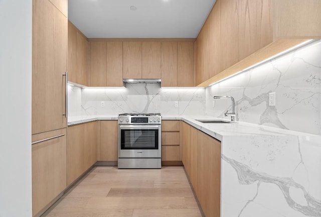 kitchen with light stone countertops, tasteful backsplash, stainless steel gas stove, sink, and light brown cabinetry