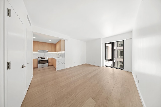 unfurnished living room featuring light wood-style floors, baseboards, and a sink