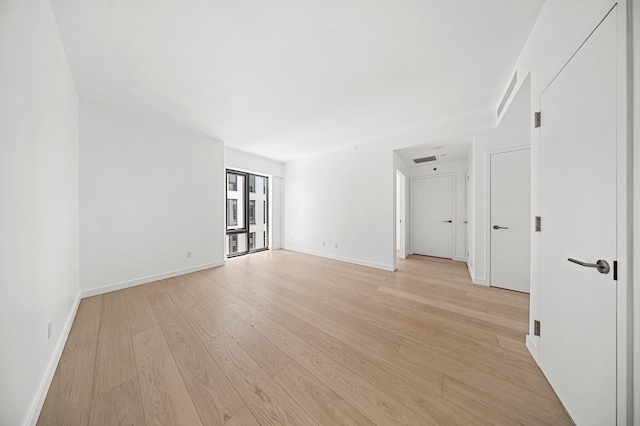 spare room featuring light wood-type flooring, baseboards, and visible vents