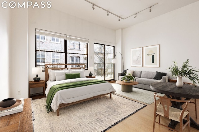 bedroom featuring access to exterior, rail lighting, and wood-type flooring