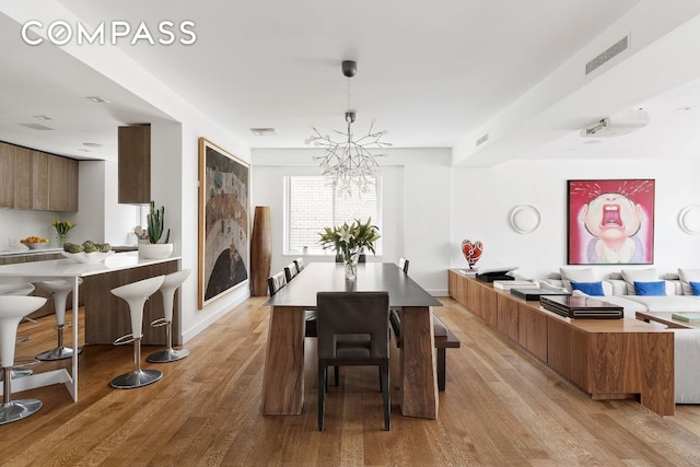 dining area with light hardwood / wood-style floors and a notable chandelier