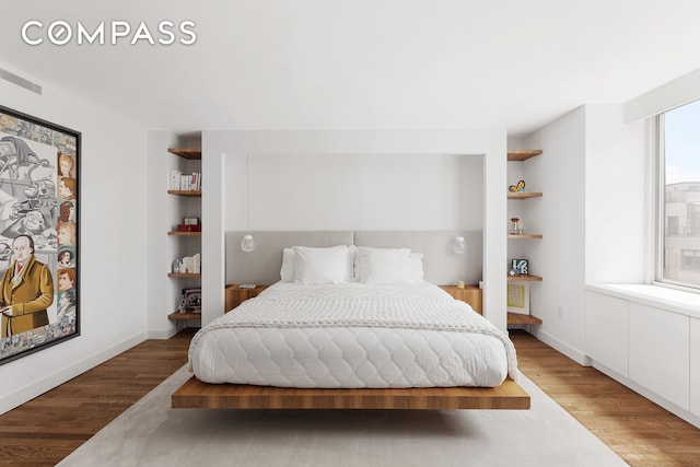 bedroom with light wood-style flooring, visible vents, and baseboards