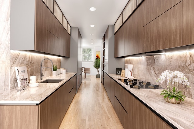 kitchen featuring a sink, stovetop, modern cabinets, and light wood-style flooring