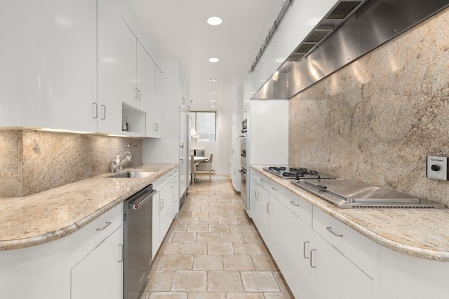 kitchen featuring sink, wall chimney range hood, white cabinets, stainless steel appliances, and backsplash