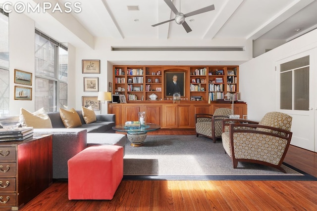 living room featuring beam ceiling, dark hardwood / wood-style floors, and built in shelves