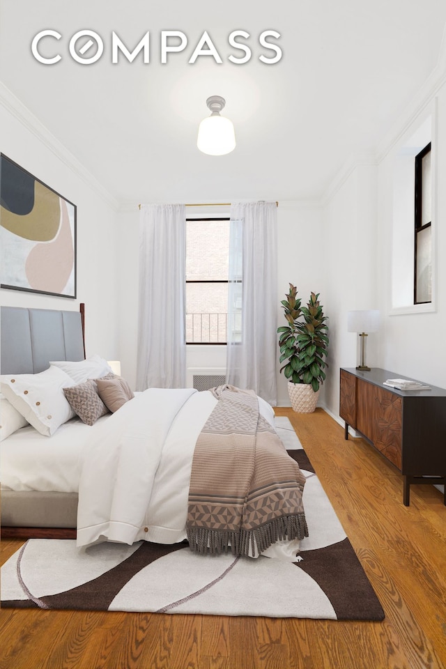 bedroom featuring ornamental molding and wood finished floors