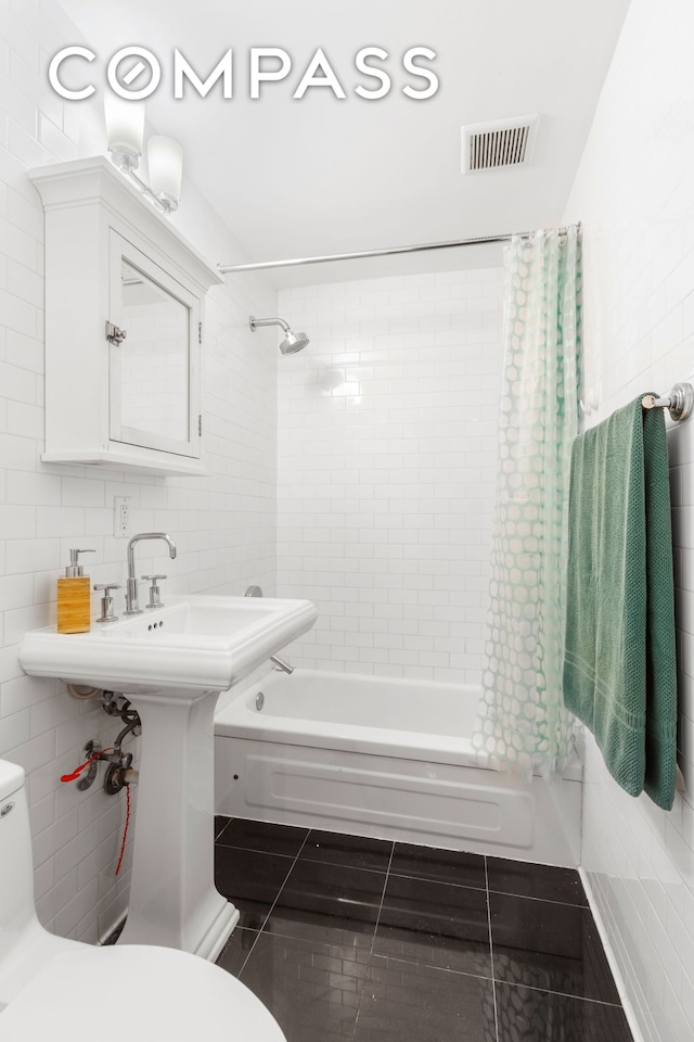 bathroom with tile patterned floors, visible vents, toilet, shower / bath combo, and tile walls