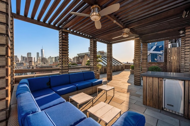 patio terrace at dusk featuring a bar, outdoor lounge area, and ceiling fan