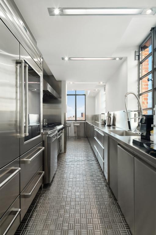 kitchen featuring sink, built in refrigerator, stainless steel counters, wall chimney range hood, and stove