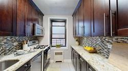 kitchen featuring gas range oven, light stone countertops, stainless steel dishwasher, and decorative backsplash