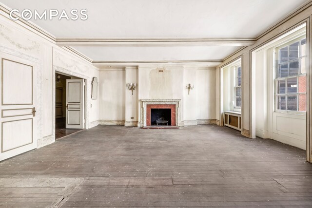 unfurnished living room featuring wood-type flooring, ornamental molding, and beamed ceiling