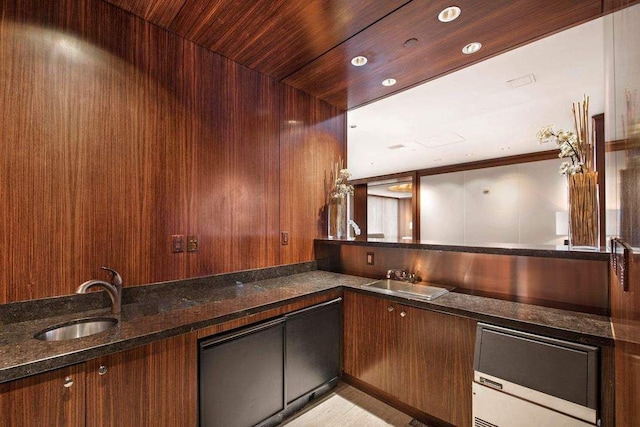 kitchen featuring crown molding, sink, dark stone countertops, and wooden walls