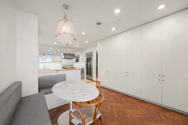 dining space featuring an inviting chandelier, sink, and dark parquet floors