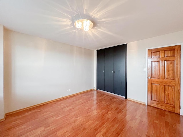 unfurnished bedroom with a notable chandelier, hardwood / wood-style flooring, and a closet