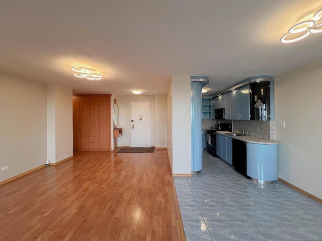 kitchen with tasteful backsplash, sink, wood-type flooring, and black appliances