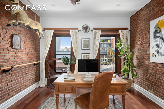 office featuring baseboards, wood finished floors, and brick wall