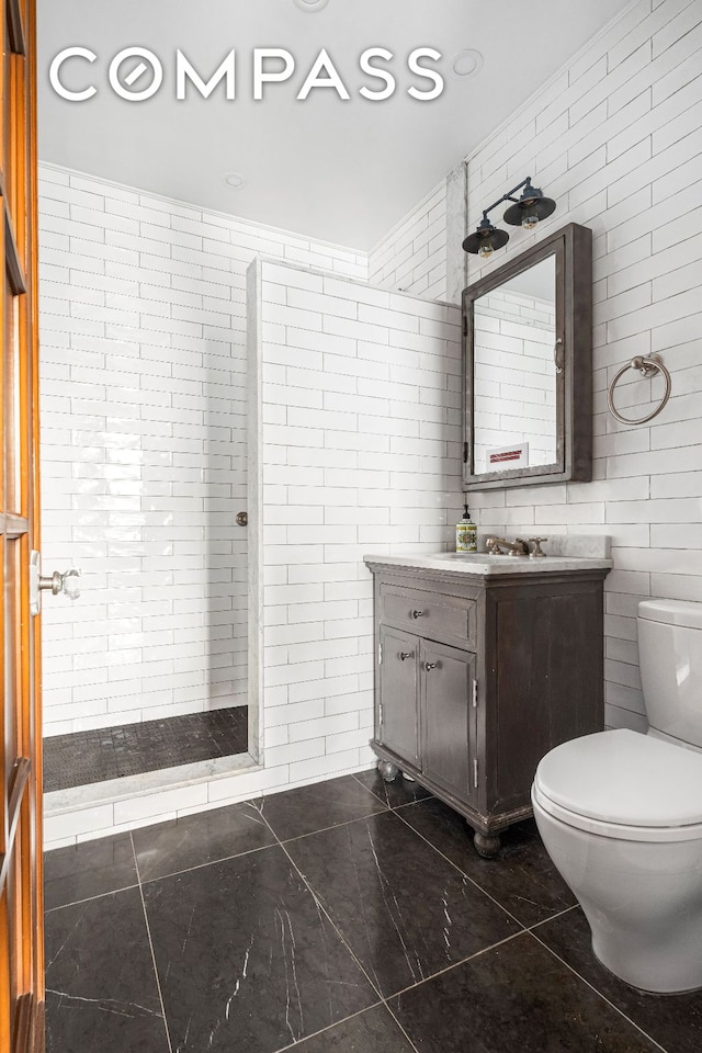 bathroom featuring tile walls, toilet, a shower stall, and vanity