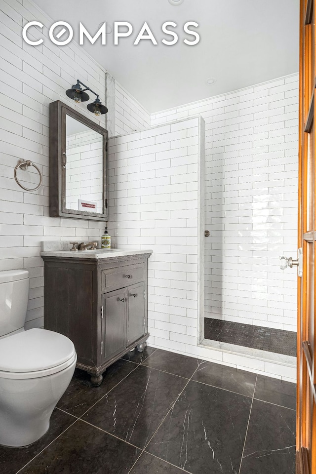 full bath featuring toilet, tiled shower, tile walls, and vanity