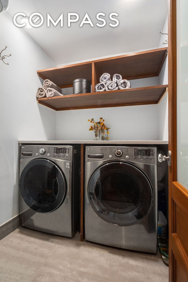 washroom featuring laundry area, light tile patterned flooring, baseboards, and washing machine and clothes dryer