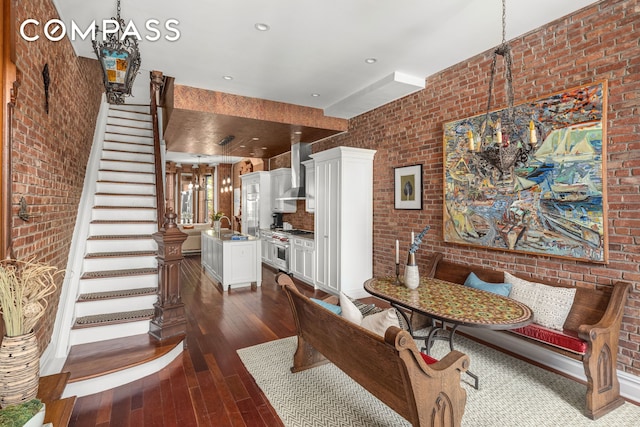 dining space with dark wood finished floors, brick wall, breakfast area, stairs, and recessed lighting