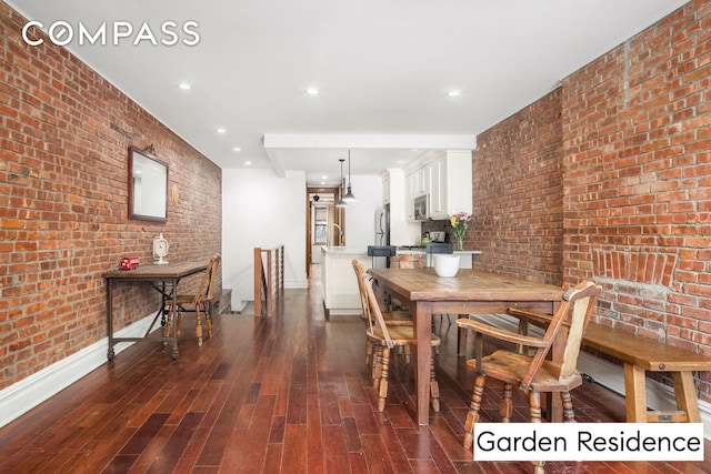 dining area featuring brick wall, baseboards, dark wood finished floors, and recessed lighting