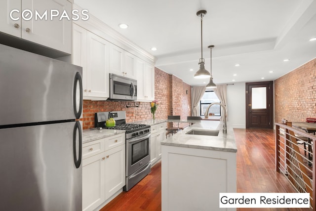 kitchen featuring a sink, dark wood finished floors, stainless steel appliances, brick wall, and white cabinets