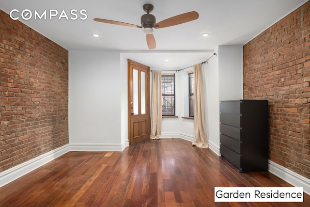 foyer featuring dark wood-style floors, brick wall, and baseboards