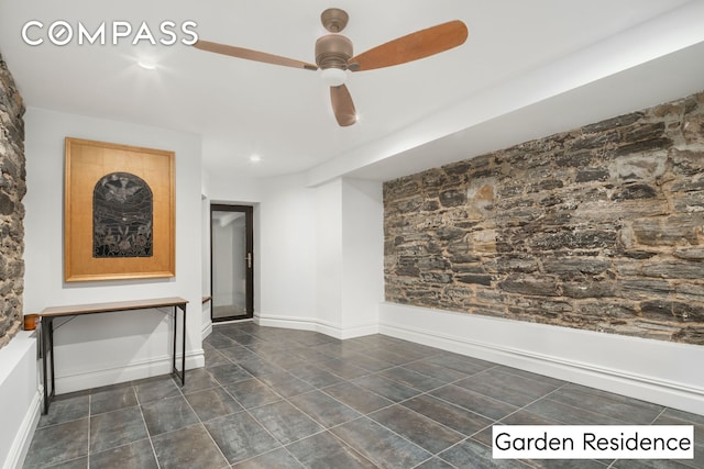 interior space with a ceiling fan and baseboards