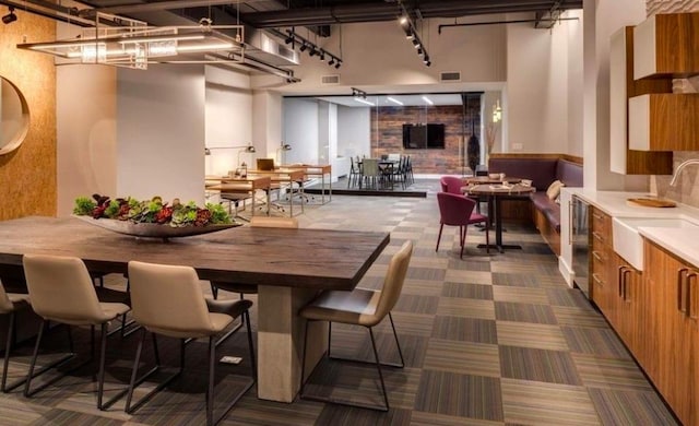 dining area with dark colored carpet, visible vents, and a high ceiling