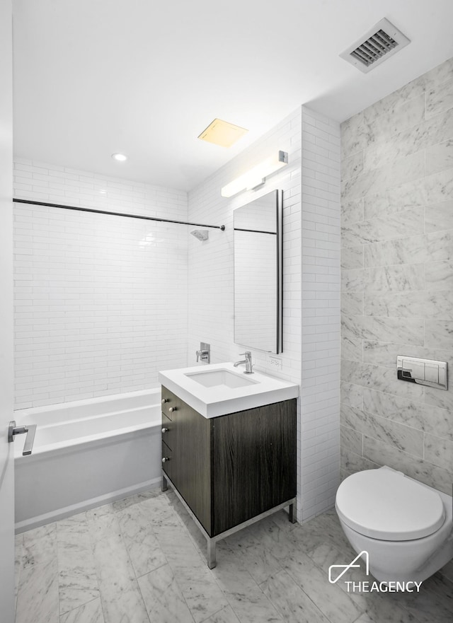 bathroom featuring toilet, vanity, visible vents, tile walls, and marble finish floor