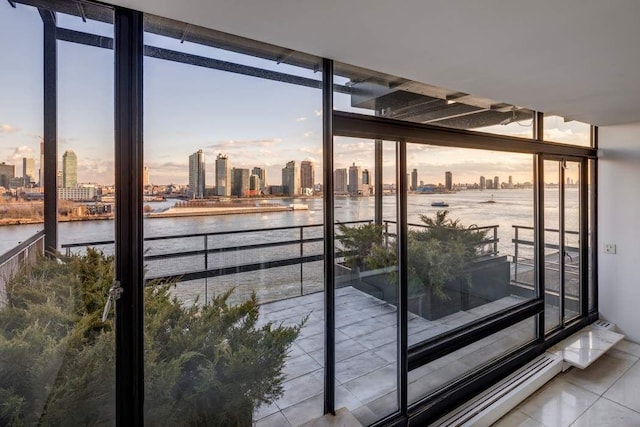 doorway with expansive windows, a water view, tile patterned flooring, and a city view