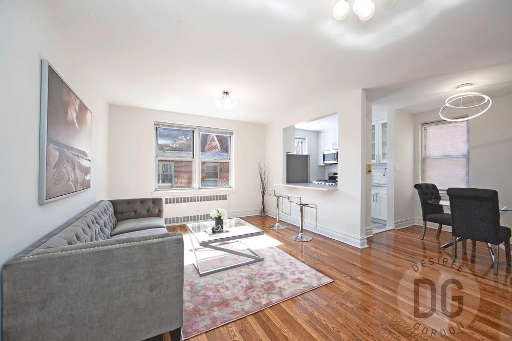living area with radiator heating unit, plenty of natural light, wood finished floors, and baseboards