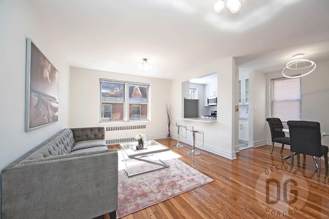 living area with radiator heating unit, plenty of natural light, wood finished floors, and baseboards