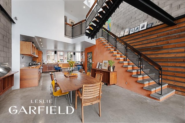 dining area featuring a towering ceiling, finished concrete floors, and stairway