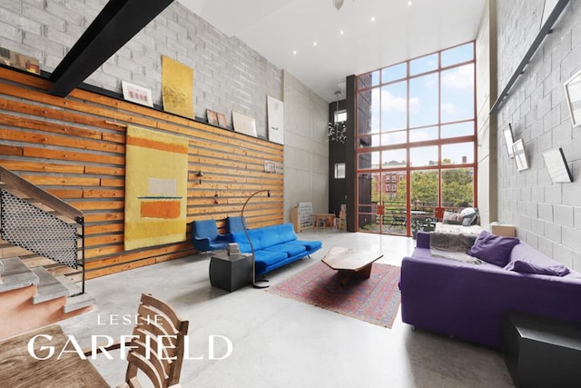 living area with concrete flooring, a high ceiling, and expansive windows