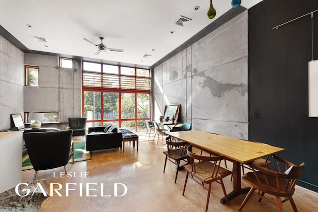 dining room with a towering ceiling, plenty of natural light, concrete floors, and visible vents