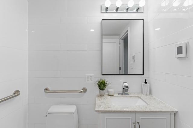 bathroom with toilet, tile walls, and vanity