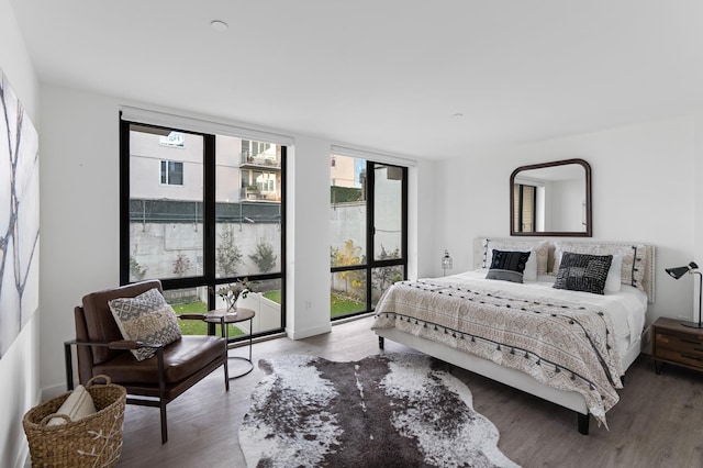 bedroom featuring a wall of windows and wood finished floors