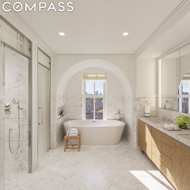 bathroom featuring a freestanding bath, tile walls, a sink, and double vanity