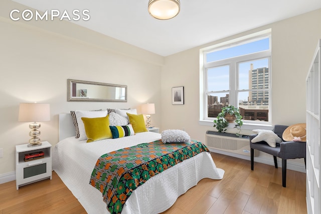 bedroom with a view of city, wood finished floors, and baseboards