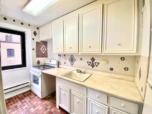 kitchen with white range with gas cooktop, sink, and baseboard heating