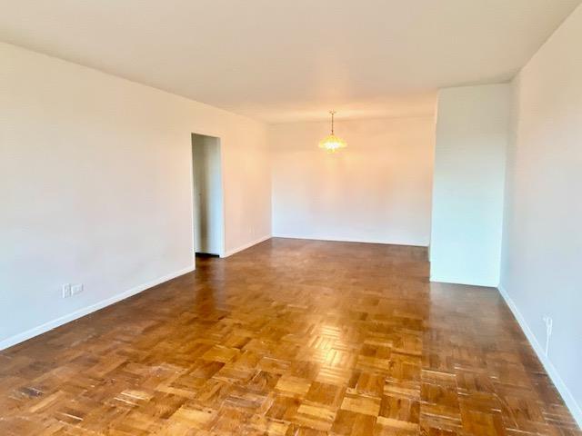 spare room featuring dark parquet flooring and a chandelier