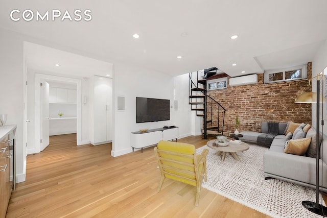 living area with stairway, brick wall, a wall mounted AC, and light wood-style flooring