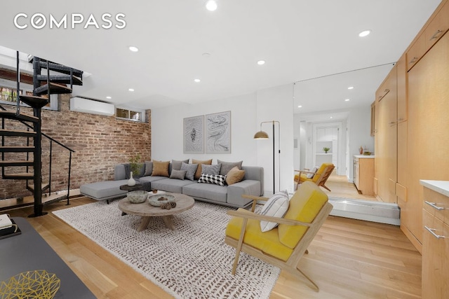 living room with brick wall, an AC wall unit, and light wood-type flooring