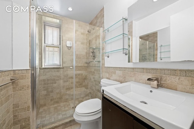 bathroom featuring toilet, tile walls, a stall shower, and vanity